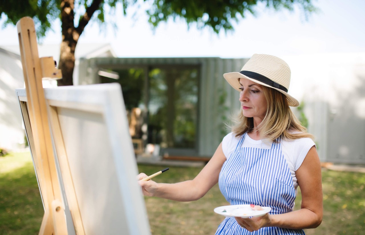 Middle Aged blonde woman painting while enjoying the sun in her luxury house